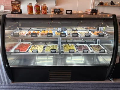 Zio's Market prepared foods case with arancini, meatballs, olives, and roasted peppers